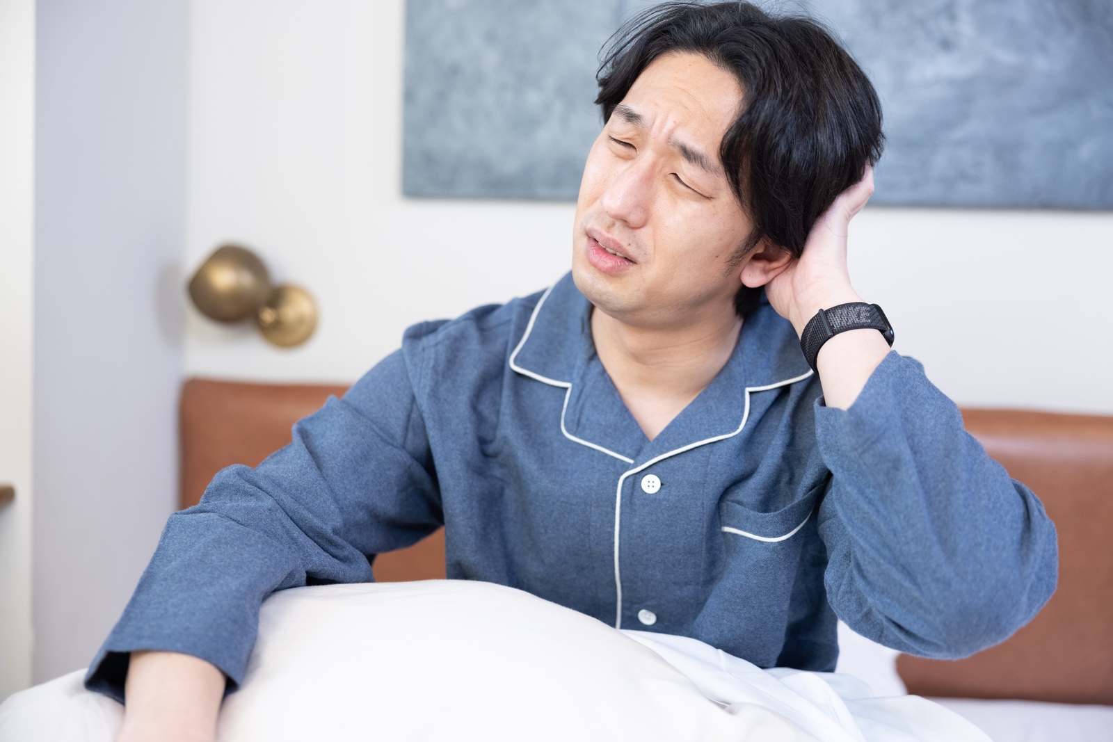 睡眠不足の状態が続いて自律神経のバランスが乱れて疲れが取れない男性