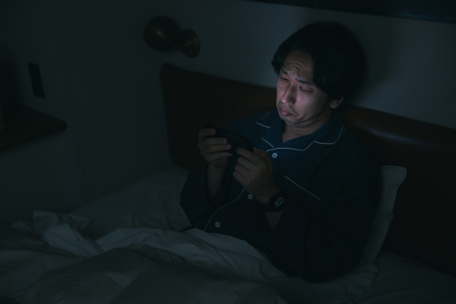 寝る直前までスマートフォンを使い眠れなくなっている男性